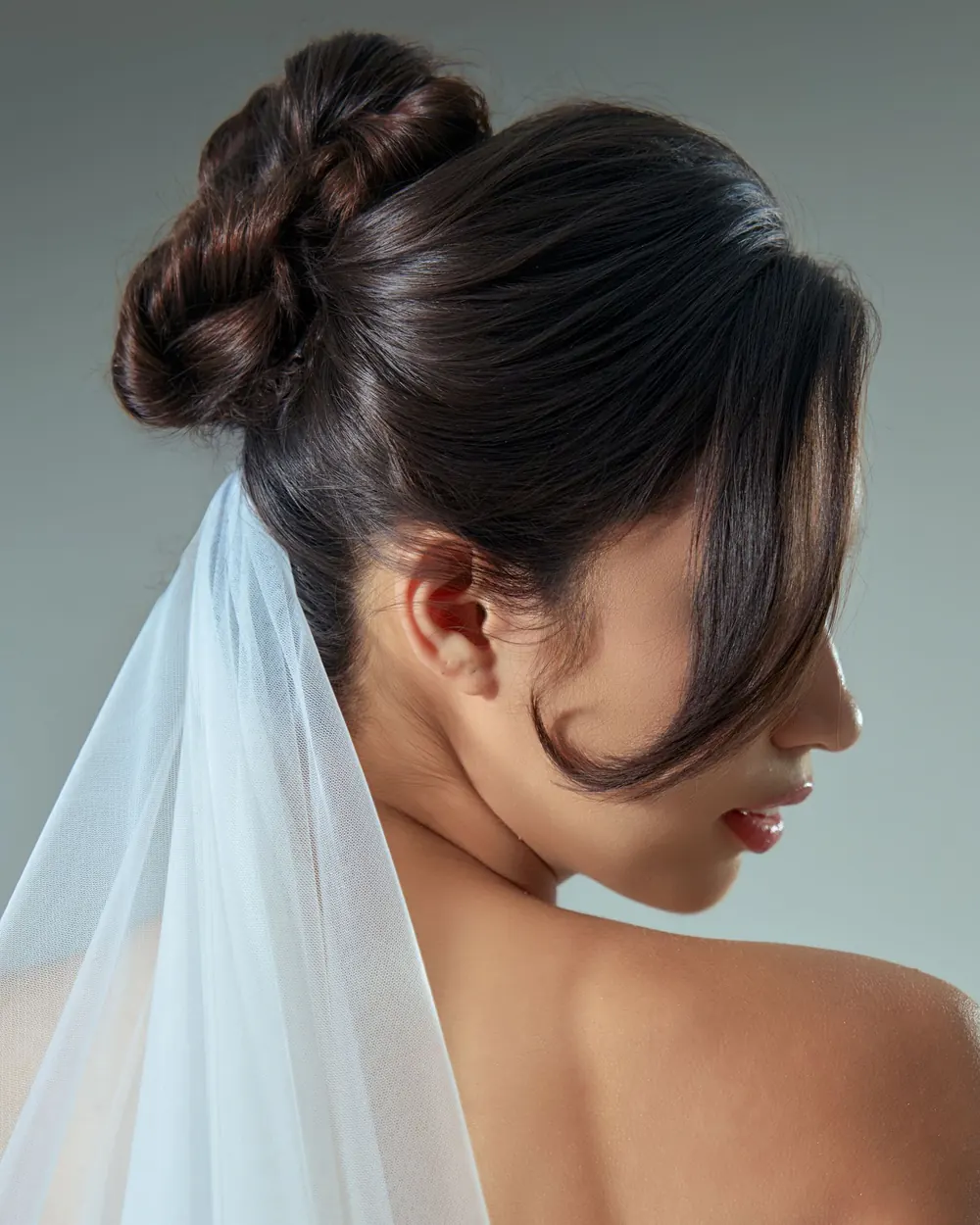 Elegant profile portrait of a bride showcasing an intricate updo with a white veil.