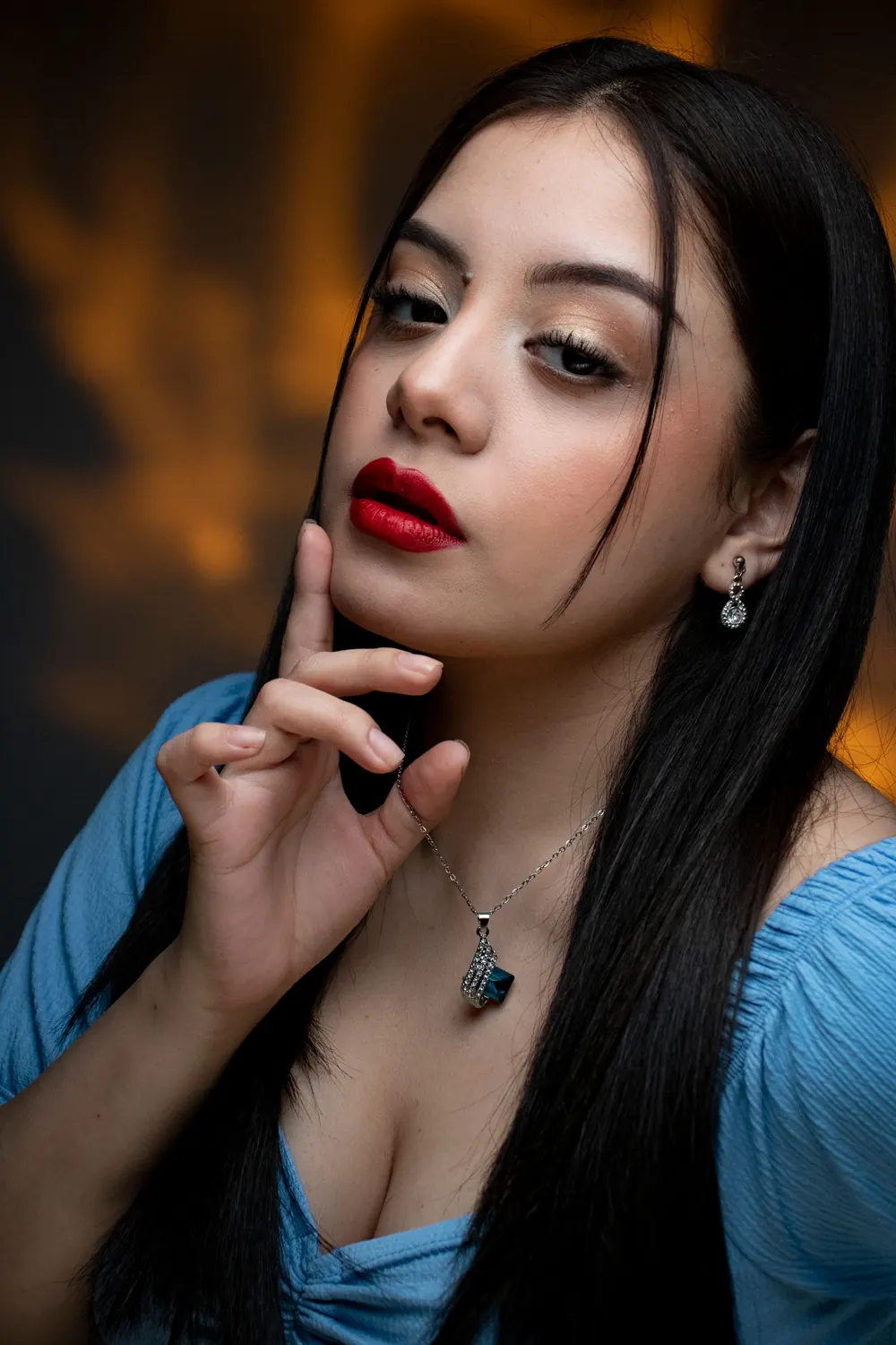 Close-up portrait of a stylish young woman with striking red lipstick and jewelry.