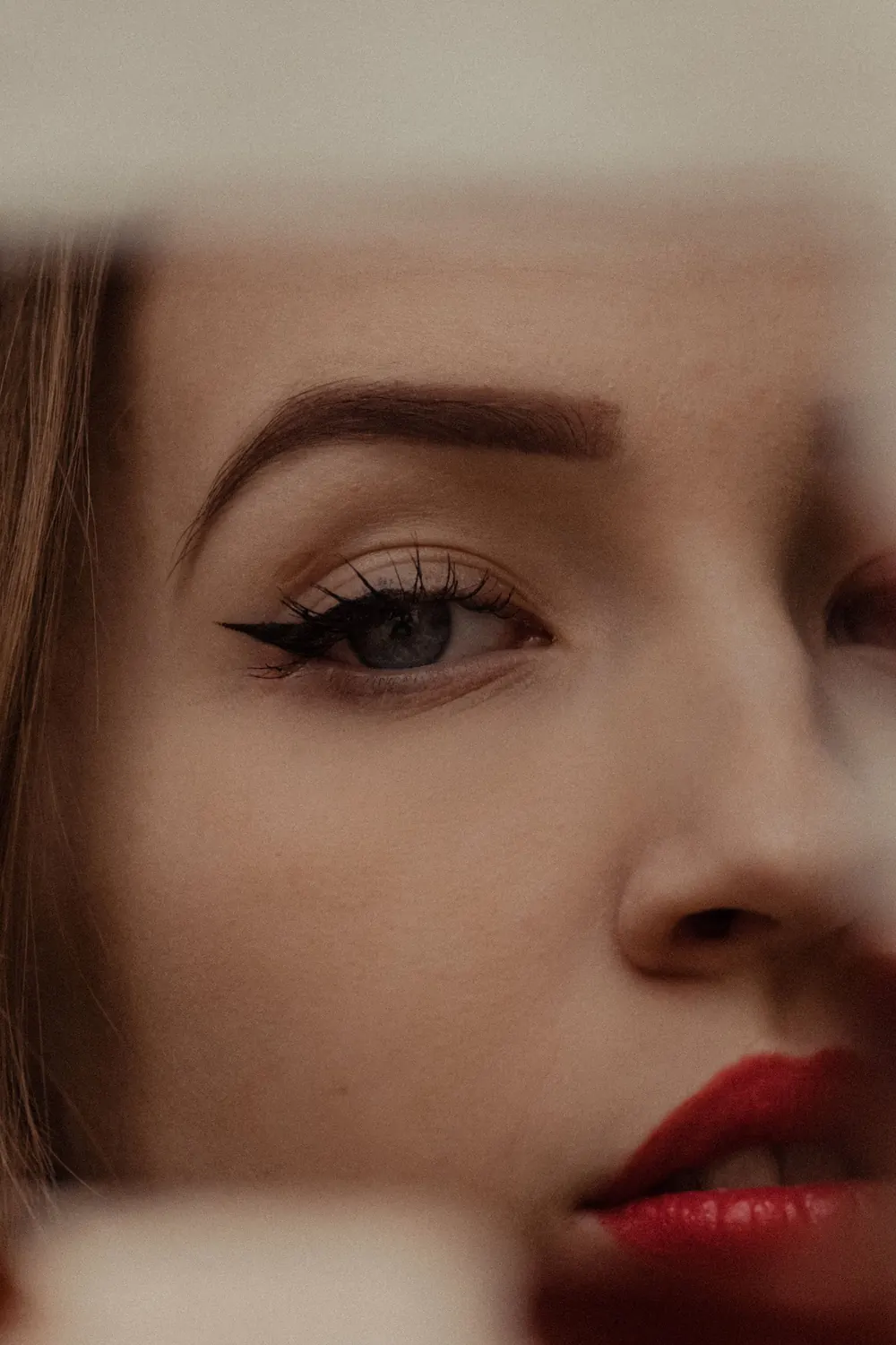Artistic close-up portrait of a woman with striking eye makeup and red lips.