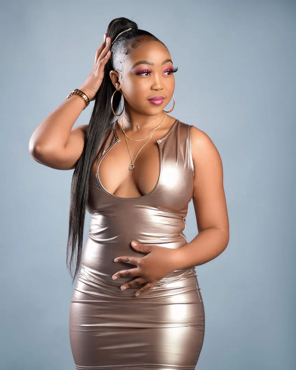 Stylish studio portrait of a confident woman in a glamorous leather dress, posing elegantly.