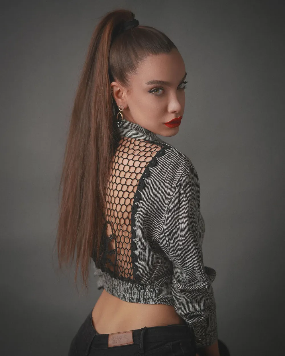 Stylish model with long hair posing in a textured outfit, showcasing elegance.