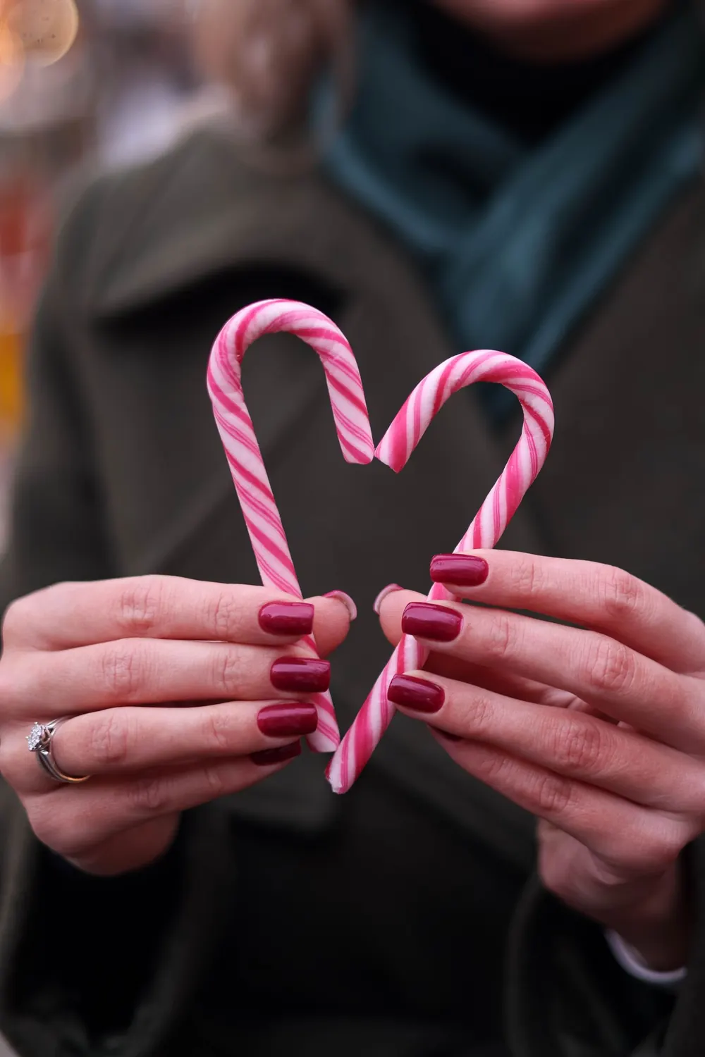 Close-up of woman's hands forming a heart with candy canes, symbolizing love.